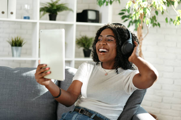 istock Young african woman using digital tablet and smiling while resting at home. 1448452698