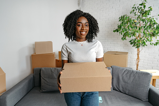 Happy african young woman with many cardboard boxes at home portrait