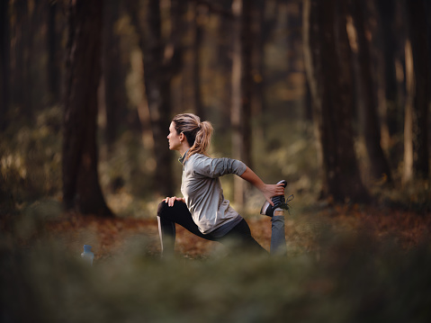 Young athletic woman doing stretching exercises during a sports training in autumn day, Copy space. Photographed in medium format.