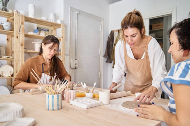 istock Women wearing aprons in a ceramics workshop creating clay pieces. 1448456047