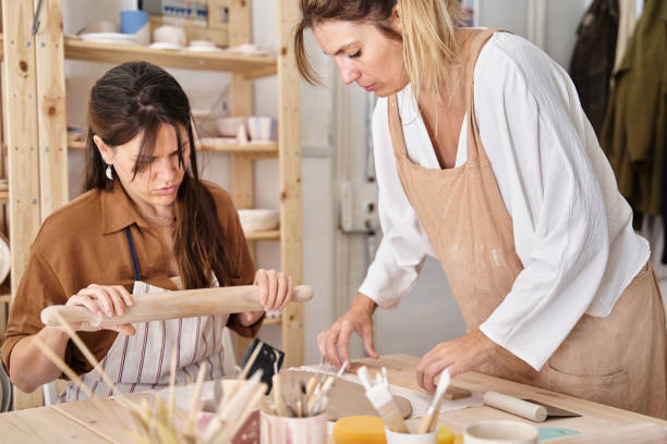 istock Women wearing aprons in a ceramics workshop creating clay pieces. 1448456082