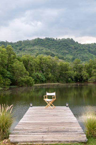 istock Folding Chair on wooden plank footway at pond 1448459066