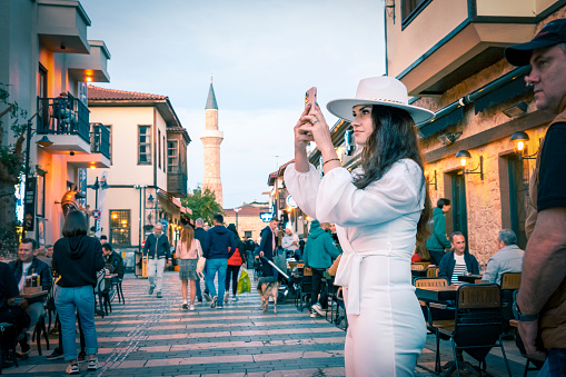 Antalya, Turkey - 12/03/2022: A young female tourist taking photos for social media on the streets of historic Old Town.