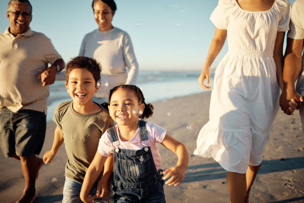 행복한 가족, 해변 휴가 및 부모와 조부모와 함께 여름에 재미있는 활동적인 활동을 하는 아이들. 웃고, 유대감을 형성하고, 기쁨을 쫓는 동안 남자, 여자, 아이들이 휴일에 노는 동안 - beach women joy sand 뉴스 사진 이미지
