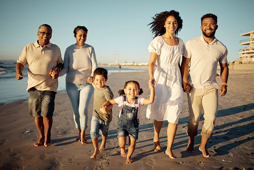 Portrait of happy family with little kids walking together on beach during sunset. Adorable little children bonding with mother, father, grandmother and grandfather outdoor on summer vacation