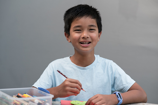 Active kid playing at home coloring with big smile looking at camera.