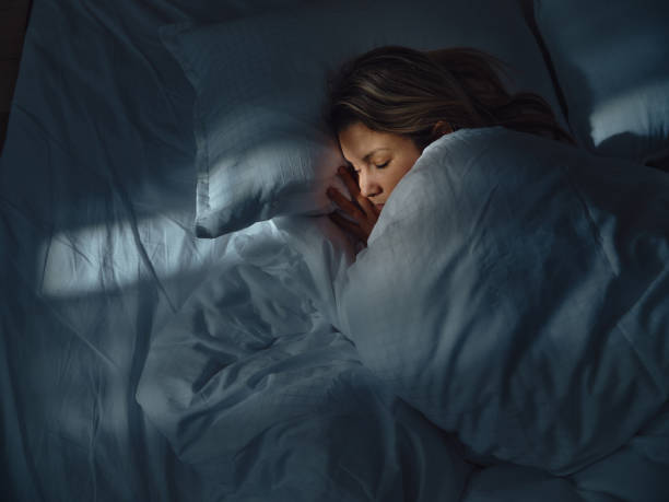 vue ci-dessus d’une femme détendue dormant au lit la nuit. - woman sleeping photos et images de collection