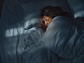 Above view of relaxed woman sleeping in bed at night.
