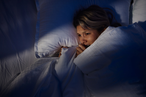 Fearful woman lying in bed at night.