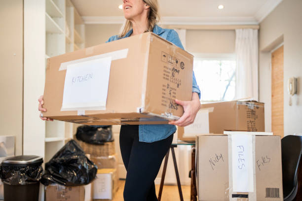 istock Woman walking with a box while moving into her new home 1448464087