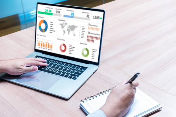 istock Businessman hand holding pen to take note on notebook with laptop display show slide presentation 1448465784