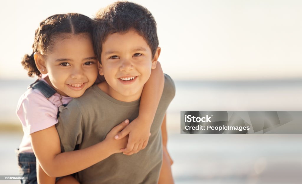 Happy, smile and portrait of siblings at the beach hugging and playing while on summer vacation. Happiness, ocean and brother giving his sister a piggyback ride while on a seaside family holiday. Child Stock Photo