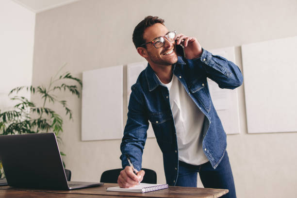 istock Smiling businessman writing notes during a phone call 1448467463