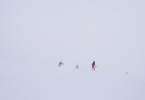 Skiers on a mountainside during a snow storm.