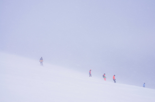 Skiers on a mountainside during a snow storm.