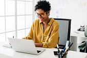 istock Graphic designer smiles as she works on a laptop in an office 1448474701