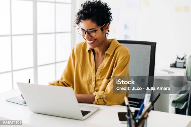 Graphic Designer Smiles As She Works On A Laptop In An Office Stock Photo - Download Image Now