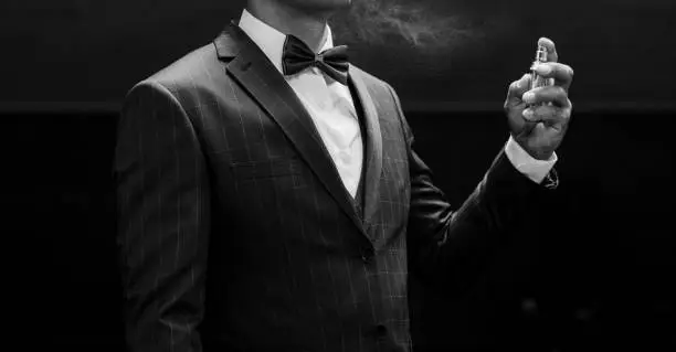 Photo of man in suit using perfume