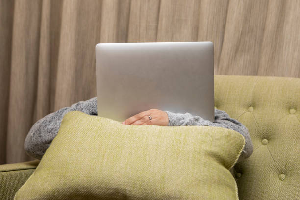 Person using a laptop computer with their face hidden behind the screen