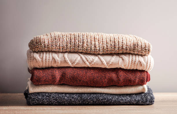 istock Bunch of knitted warm  color sweaters with different knitting patterns stacked in  pile on wooden table. Fall winter season knitwear. 1448475289