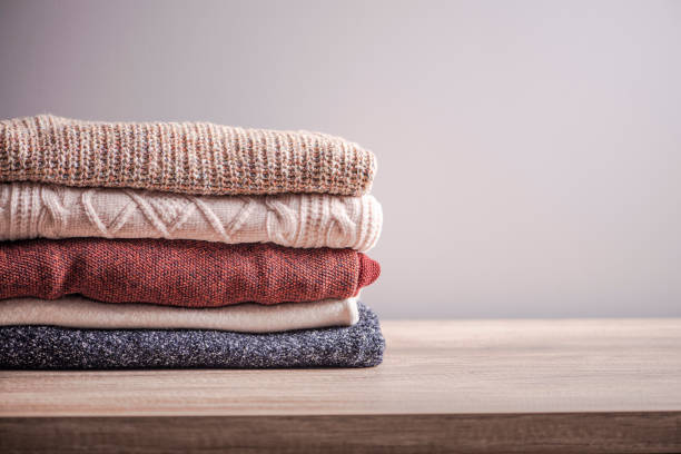istock Bunch of knitted warm  color sweaters with different knitting patterns stacked in  pile on wooden table. Fall winter season knitwear. 1448475311