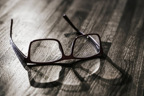 istock Old glasses with shadow on wooden table surface closeup 1448475498