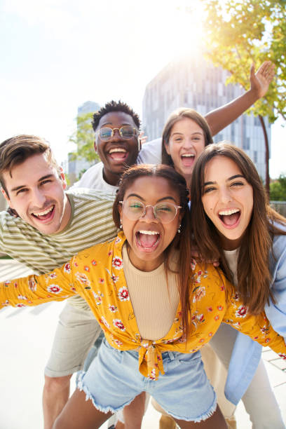 giovani amici felici che cercano la macchina fotografica e ridono gruppo sorridente di persone che si divertono insieme all'aperto - people multi ethnic group cheerful young adult foto e immagini stock