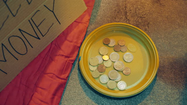 Close up of beggar's plastic plate with coins in it