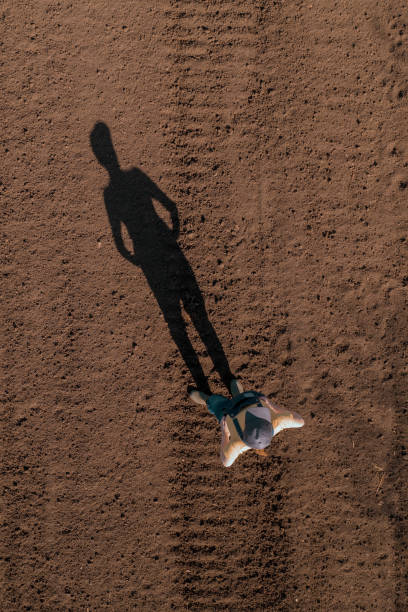 istock Female farmer standing in ploughed field casting long shadow on the ground 1448477000
