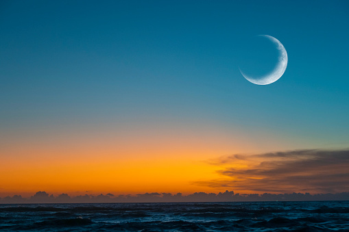 New moon or Ð¡rescent above ocean. Half Moon on bright evening sky, space for text