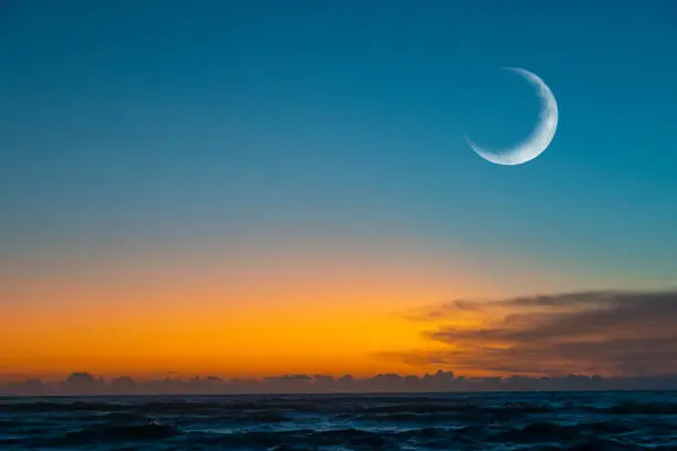 New moon or Ð¡rescent above ocean. Half Moon on bright evening sky, space for text