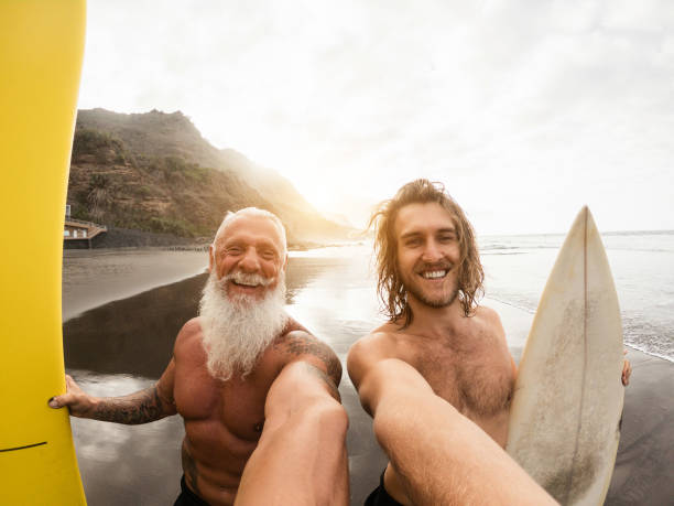 Father and son having fun doing selfie on the beach after surf session - Soft focus on guy face
