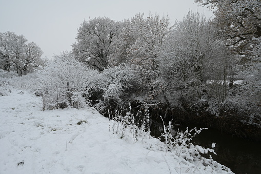 A cold, dull snow covered morning in Horley, Surrey by the River Mole on 12 Dec 2022.