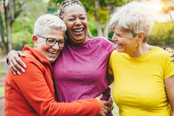 Multiracial senior women having fun together after sport workout outdoor - Focus on left woman face stock photo