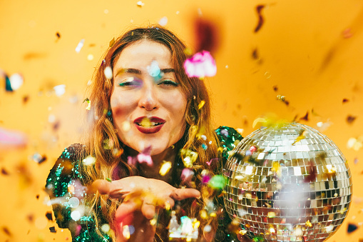 happy girl blowing confetti holding vintage disco ball - Focus on face