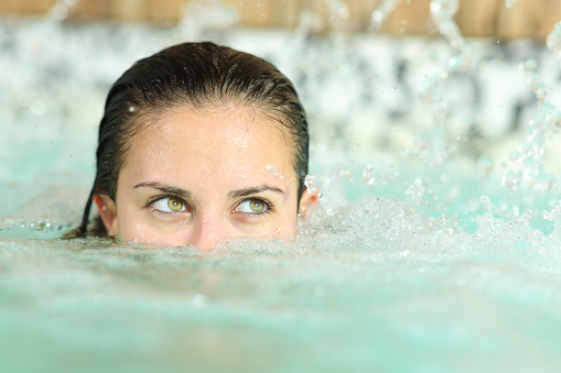 Woman with beauty eyes looks at side in spa pool