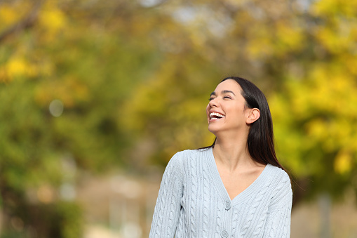 Happy woman walking in a park laughing looking at side
