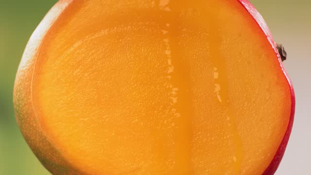 Halving Mango and Juice flows down the surface of rotating Halved King Mango. Slow Motion
