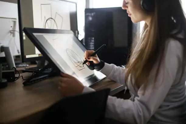 Photo of Young woman drawing using a pen tablet