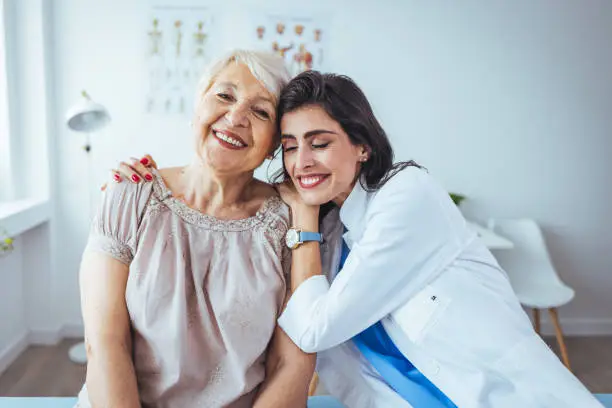 The elderly woman enjoys an embrace from her favorite home healthcare nurse. Medical care, young female doctor hugging patient. Empathy concept. Elderly woman hugging caregiver