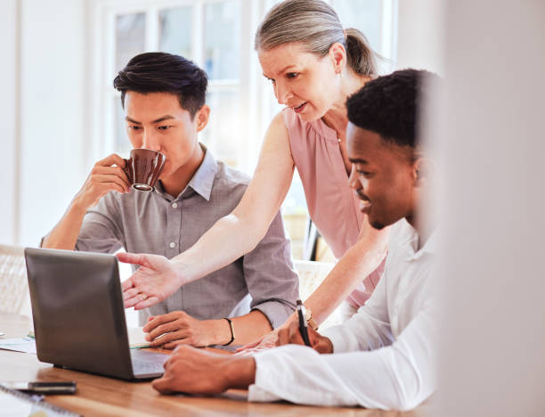 istock Training, laptop and startup team with leader working in modern office. Teamwork, collaboration and diversity, ceo business woman coaching men at project workshop at social media management company. 1448490095
