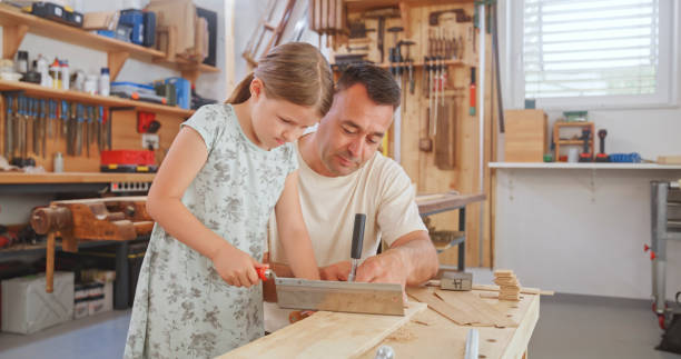 istock Father and daughter cutting wooden plank 1448491858
