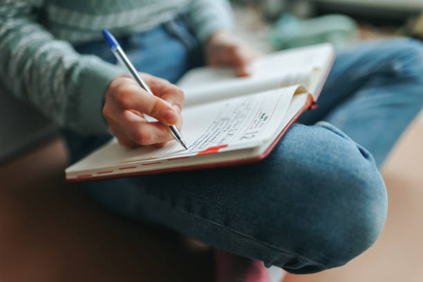 istock Unrecognizable woman sits on floor of house and writes notes in notebook. 1448493136