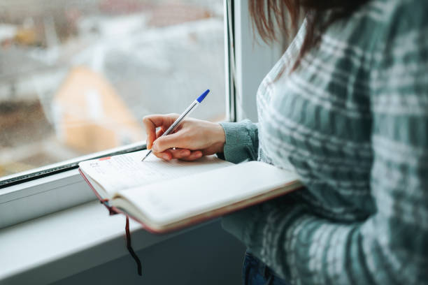 istock Hand of woman unrecognizable writes down necessary words with notepad for notes, pen on paper. 1448493140