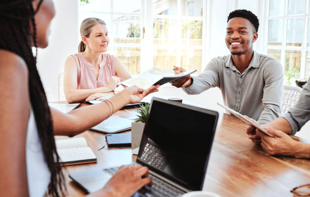 istock Documents, collaboration and business people in a meeting planning creative marketing, advertising and logo branding. Team, diversity and black woman giving a happy man portfolio report paperwork 1448493528