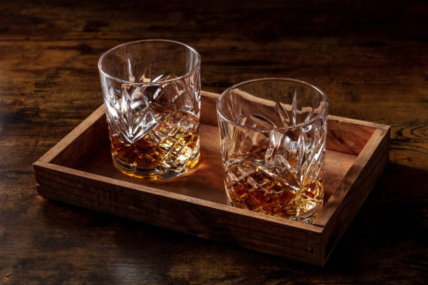 Whiskey in glasses with ice. Bourbon whisky on rocks on a dark rustic background stock photo