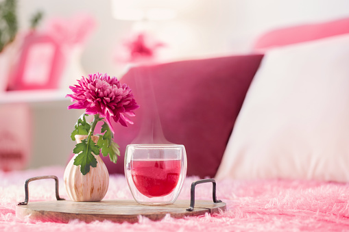 red tea in thermo glass with flowers in modern bedroom in trendy color of year 2023