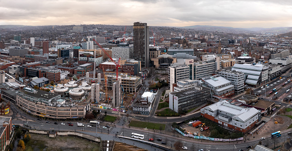 Sheffield, UK - December 6, 2022.  An aerial panorama of Sheffield Hallam University and city centre with a tall skyscraper being built on a city construction site with investment