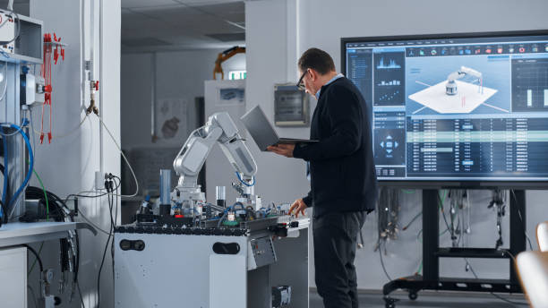 istock Male Engineer Holding Laptop, Moving Bionic Limb With Written Code And Analysing Results on Big Screen. Modern Equipment and New Era in Computer Science and Robotics Industry Concept. 1448501782
