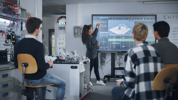 istock Teacher is Explaining Principles of Working With Robotic Hand, Showing Examples on Big Screen at Modern University. Teenagers Brainstorming and Asking Questions. Robotic Engineering Concept. 1448502226